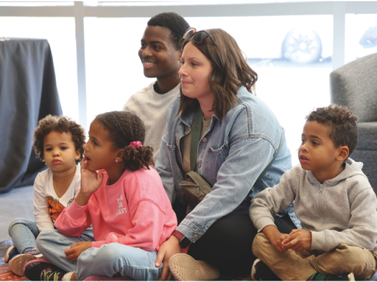 Enfants avec leurs parents, assis pour l'heure du conte.
