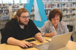 Personne aînée en train d'être aidée avec l'ordinateur.