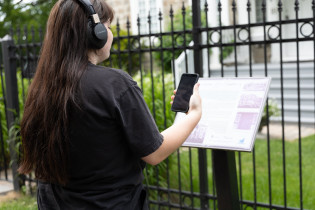 Jeune femme profitant du Baladodécouverte devant un bâtiment patrimonial.
