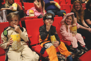 Enfants déguisés assis dans la salle de spectacle du Pôle pour la projection cinéma.