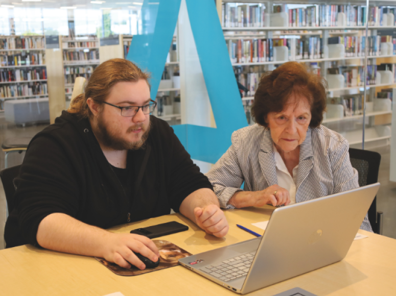 Personne aînée en train d'être aidée avec l'ordinateur.