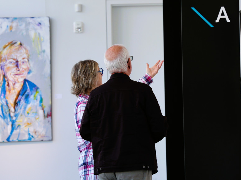 Deux personnes admirant les toiles d'une exposition au Pôle.