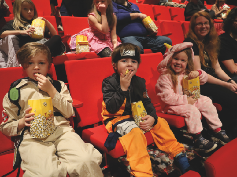 Enfants déguisés assis dans la salle de spectacle du Pôle pour la projection cinéma.