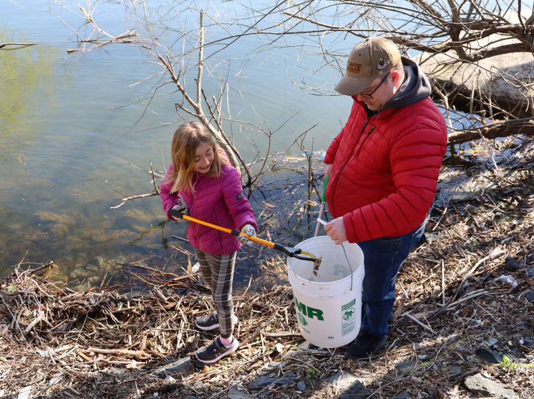 Famille ramassant des déchets sur la berge.